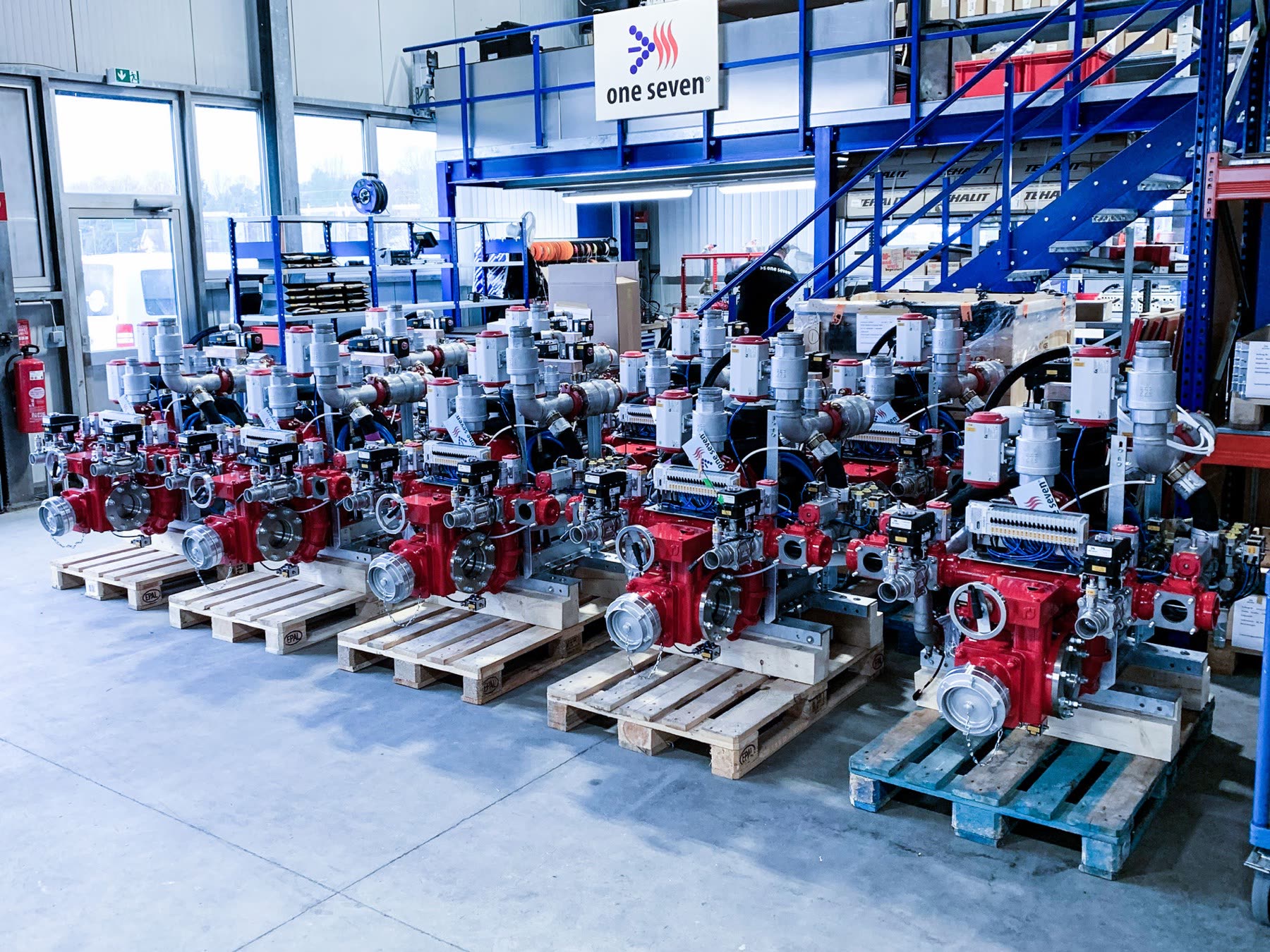 Rote Pumpen- und Armaturengruppen auf Paletten in der Halle